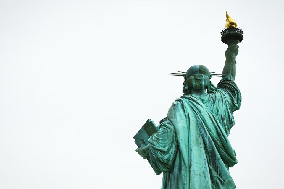 Statue of Liberty holding her torch against a pale sky