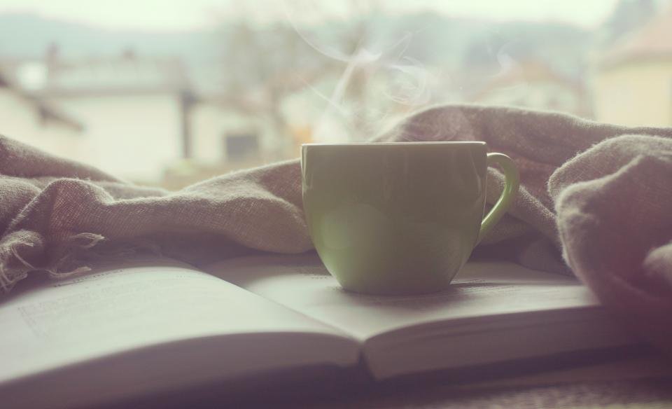 Tea cup resting on an open book, setting the scene for the best book club books