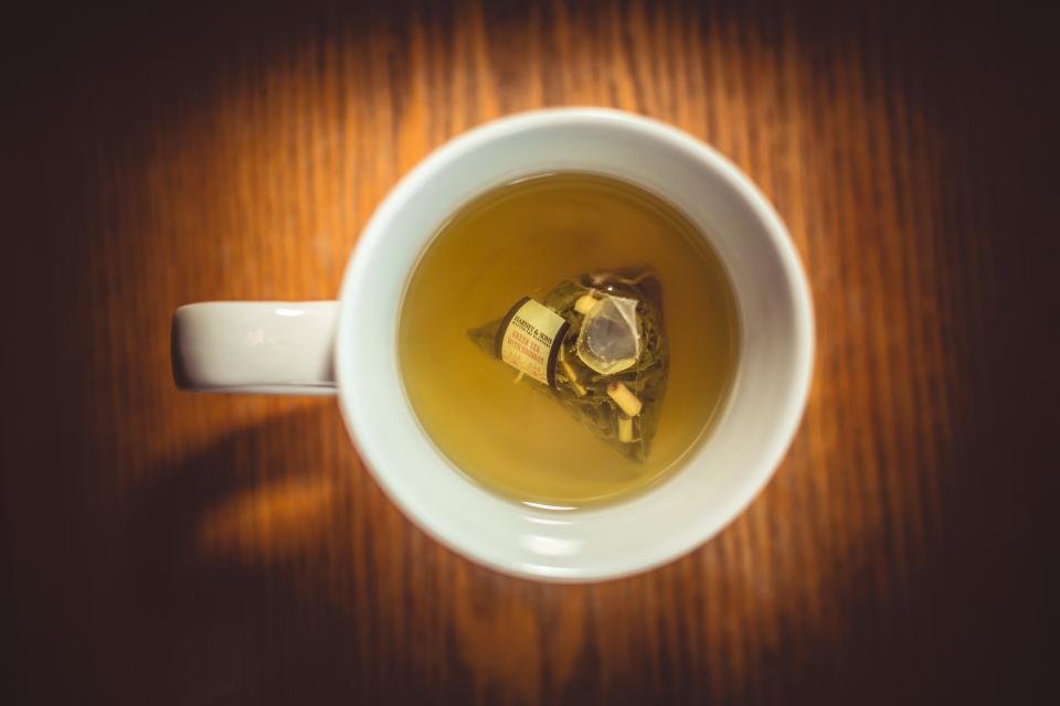 Cup of green tea with a tea bag on a wooden surface