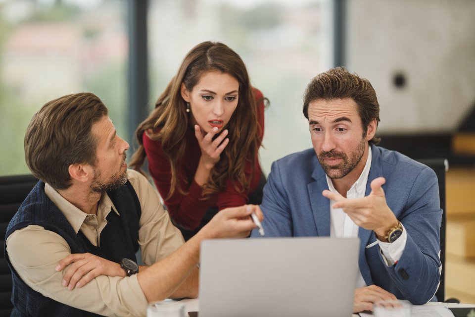 Colleagues discussing work around a laptop in an office