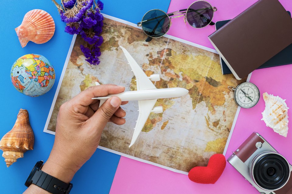 Travel planning flat lay with map, camera and toy airplane
