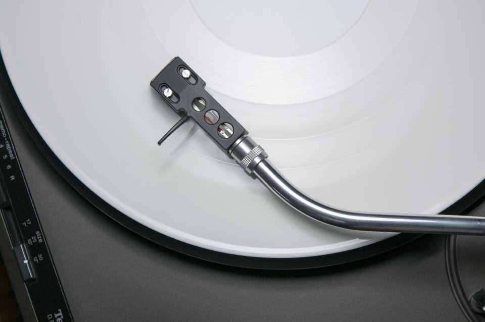 Turntable tonearm over a white vinyl record