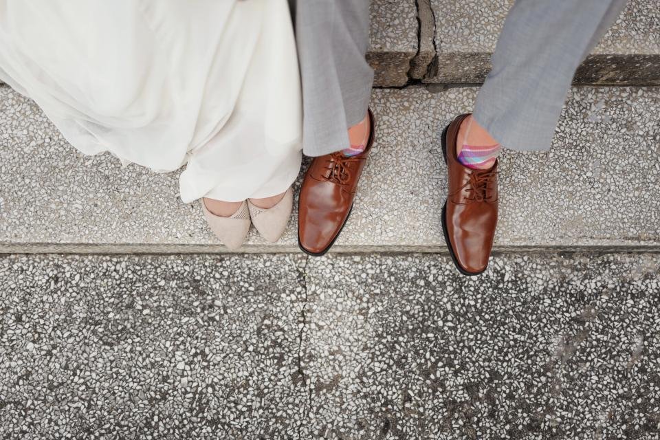 Couple standing on stone steps showing flat shoes and dress shoes