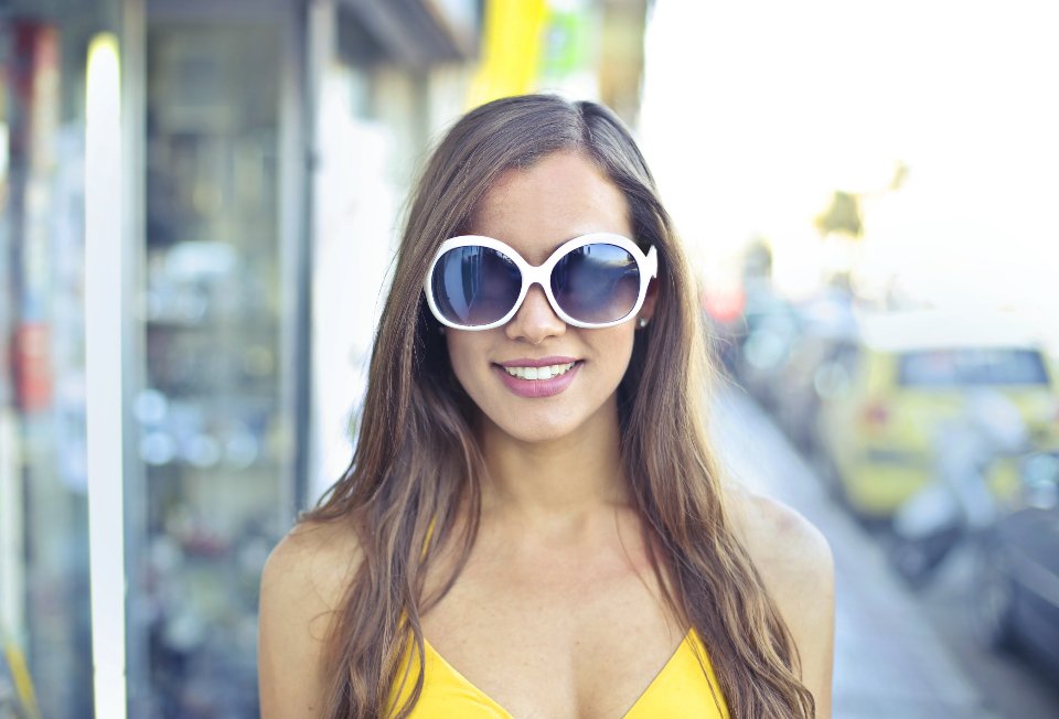 Smiling woman wearing white sunglasses in the city
