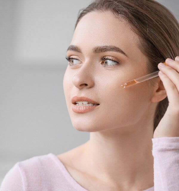 Woman applying retinol serum dropper