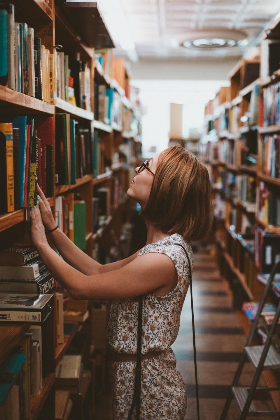 Woman browsing a bookshelf, a reader who would love gifts for book lovers