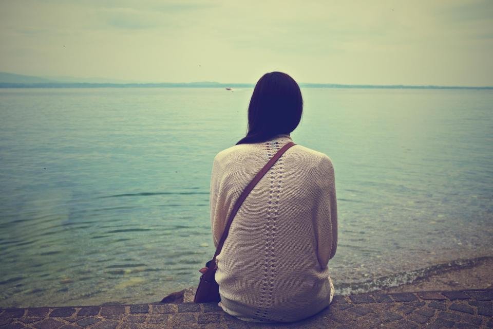 Woman in a cozy knit cardigan sitting by the water