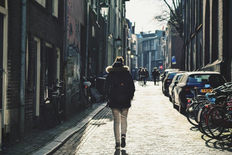 Woman walking down a cobblestone street in a long coat