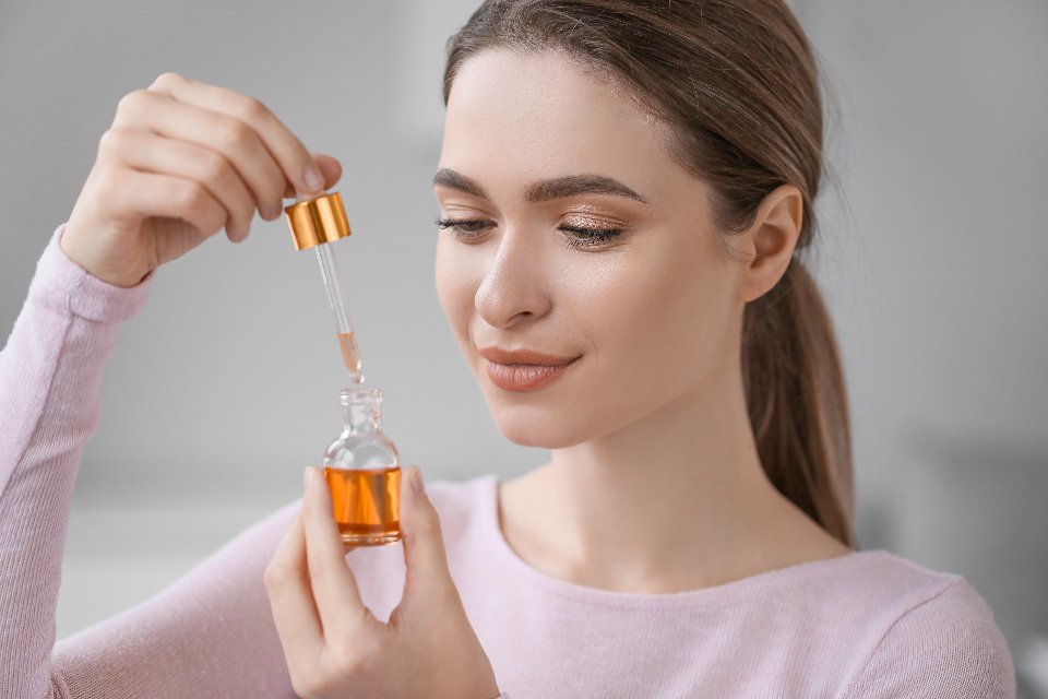 Woman holding a dropper bottle of nourishing oil