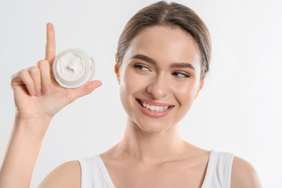 Smiling woman showing a jar of one of the best luxury moisturizers