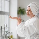 Woman skincare by bathroom window