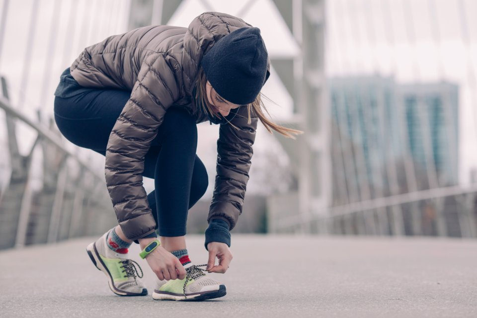 Woman in a puffer jacket and leggings tying her sneakers