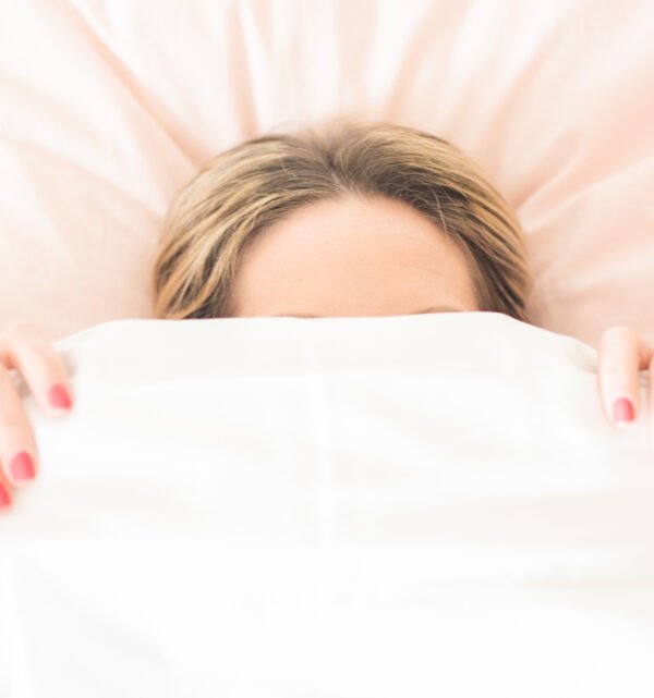Woman under white duvet