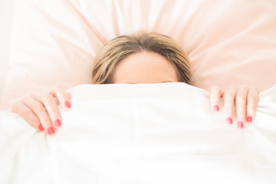 Woman under white duvet