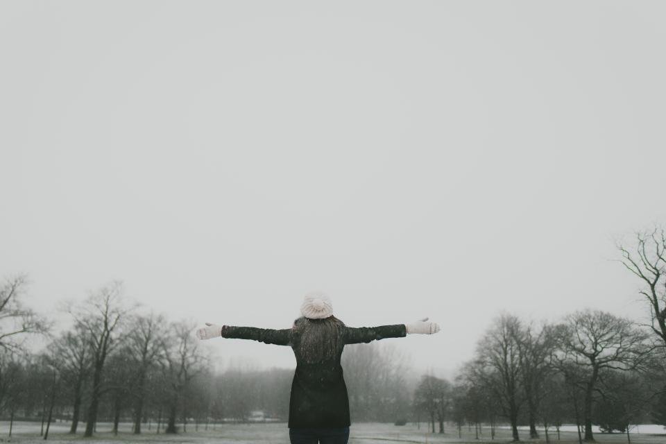 Woman standing in a foggy winter landscape with arms outstretched