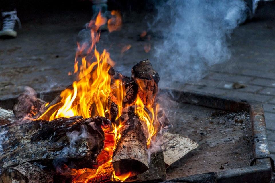 Fire pits glowing with burning logs in a backyard at dusk