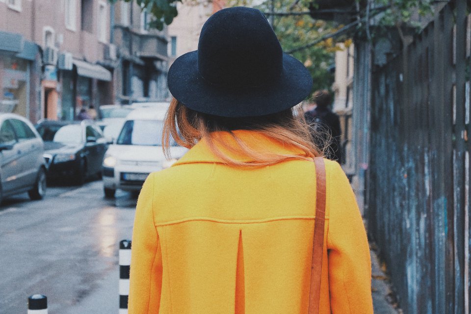 Woman in a yellow coat on a city street, one of the best wool coats for winter